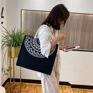 Macro detail of the ethnic mandala pattern on a large black and white canvas tote bag
