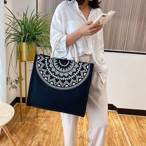 Detail of black canvas tote with white mandala pattern and thick cream rope handles