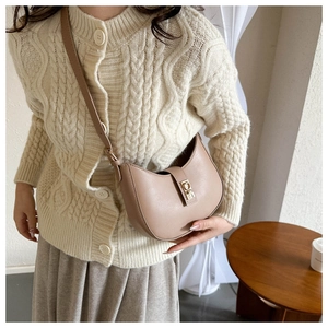 Détail d'un sac à bandoulière beige en cuir en forme de lune avec boucle dorée élégante
