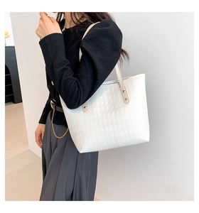 Detail of white quilted tote bag with diamond pattern, long strap and metal rivets