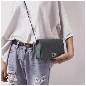 Close-up of dark green textured crossbody bag with metal twist lock and chain strap