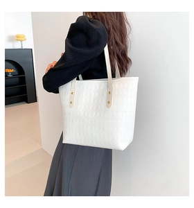 Close-up of white quilted tote bag with golden studs and geometric diamond pattern