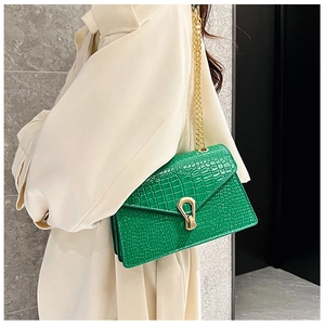 Detail of green crocodile texture shoulder bag with gold shield buckle on beige trench coat