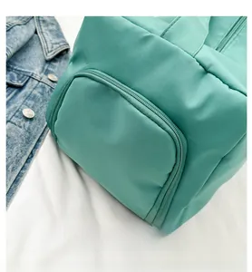 Detalle del bolso bandolera de nailon verde menta con cierre de cremallera y bolsillo