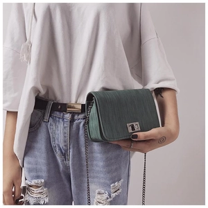 Detail of dark green textured small square bag with silver metal chain and twist lock