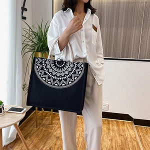 Detail of black canvas tote bag with white mandala print and rope handles on a model