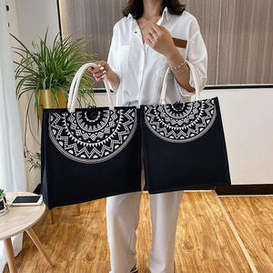 Detail of black canvas tote bags with white geometric mandala prints and rope handles