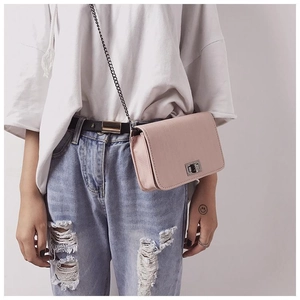 Close-up of pink textured crossbody bag with silver chain strap and twist-lock on model