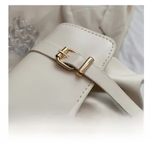Macro detail of creamy leather handbag featuring a premium gold metal buckle closure