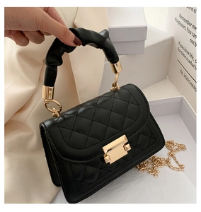 Detail der schwarzen Stepptasche aus Leder mit goldenem Drehverschluss und Raffgriff