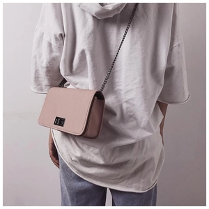 Detail of pink PU leather small crossbody bag with silver turn-lock and metal chain strap