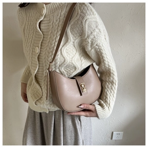 Détail d'un sac hobo kaki minimaliste avec boucle dorée sur l'épaule d'un mannequin