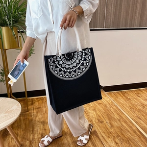Detail of black canvas tote bag with white geometric patterns and cotton rope handle
