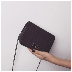 Detail showing the textured small square bag with metal chain strap and twist lock