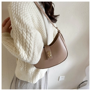 Détail d'un sac sous le bras beige en demi-lune avec finition cuir lisse et boucle en métal