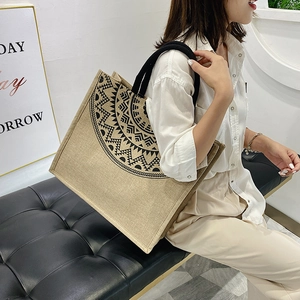 Detail of woven linen tote bag with geometric mandala print and black rope handles