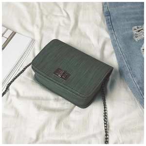 Macro shot of dark green textured leather bag with metallic twist lock and chain strap
