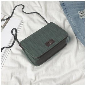 Macro view of dark green PU leather texture and rectangle metal twist lock on square bag