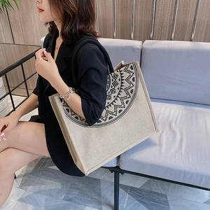 Close-up of a large linen tote bag with ethnic totem print on a model's shoulder