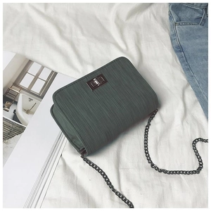 Dark green textured chain crossbody bag with metal twist lock on white fabric