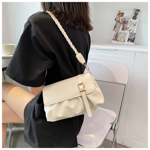 Detail of cream pleated baguette bag with gold buckle and woven shoulder strap