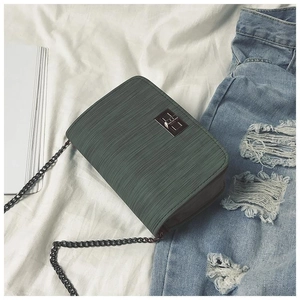 Detail view of dark green textured leather cross-body bag with golden turn-lock closure