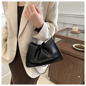Détail d'un sac seau plissé noir avec bandoulière chaîne dans un cadre moderne