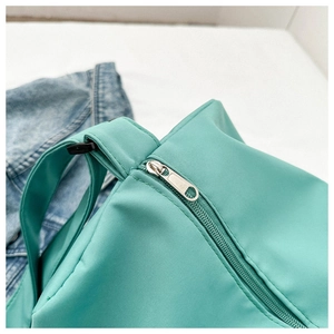 Gros plan d'un sac en nylon vert menthe montrant le zip argenté et les coutures renforcées