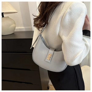 Gros plan d'un sac porté épaule demi-lune en cuir bleu clair avec boucle dorée