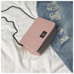 Detailed view of pink textured leather crossbody bag with silver turn-lock and chain strap