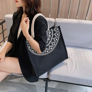 Close-up of black canvas tote bag featuring white geometric print and thick rope handles