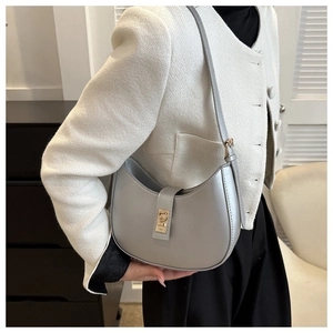 Détail du sac demi-lune argenté avec fermoir doré sur veste en tweed blanc