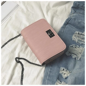 Pink textured crossbody chain bag with metal turn lock on white fabric and denim backdrop