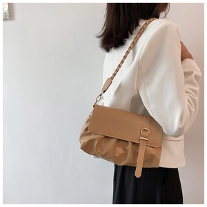 Model wearing a khaki ruched shoulder bag with a woven strap and gold buckle detail