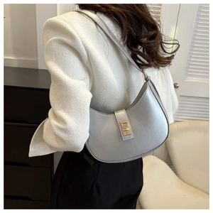 Sac sous le bras argenté en demi-lune avec boucle dorée porté avec un blazer en tweed