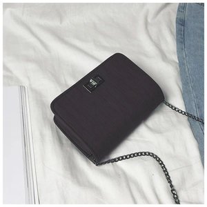 Detail of black textured crossbody bag with silver twist lock and chain strap