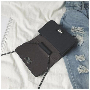 Detail of the silver twist lock and fine textured finish on the black chain shoulder bag