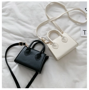 Detailed shot of mini square leather handbags in black and beige with gold hardware