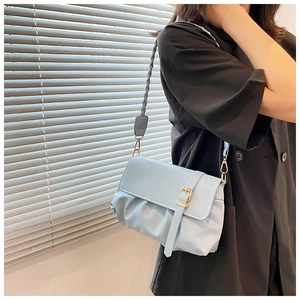 Close-up of light blue pleated PU leather bag with woven strap and gold metal buckle