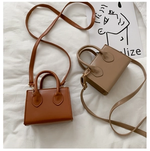 Flat lay of caramel brown and beige mini crossbody bags on white textured fabric