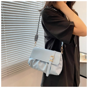 Close-up of light blue pleated shoulder bag with gold buckle and textured leather detail