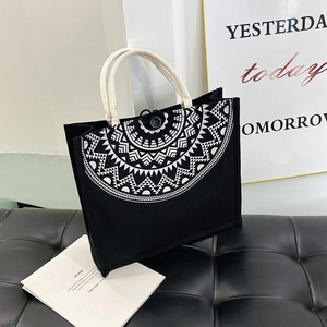 Detail of black canvas tote bag showing white geometric mandala print and rope handles