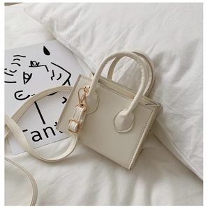Top-down view of cream mini tote bag with dual handles and gold-buckle shoulder strap