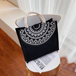 Detail of black canvas tote bag featuring white mandala pattern and rope handles