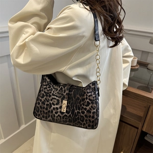 Fashionable leopard print crescent bag with gold chain and buckle shown on a model