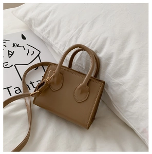 Detail view of khaki mini crossbody bag with top handles and adjustable shoulder strap