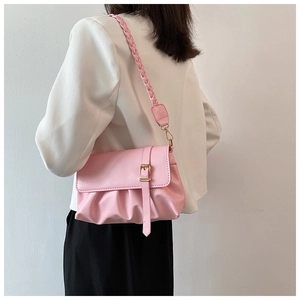 Detail of pink ruched cloud bag featuring a woven shoulder strap and golden buckle