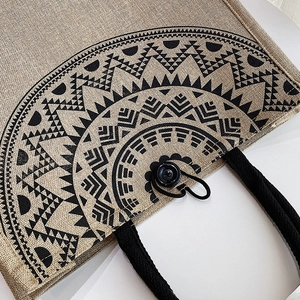 Close-up of linen tote bag with black ethnic geometric patterns and button detail