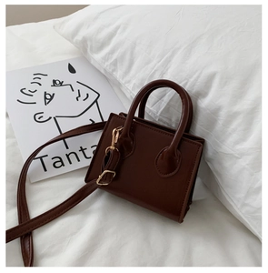 Detail of a dark brown mini handbag with smooth PU leather and gold-tone hardware buckles