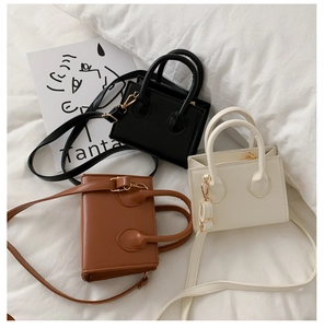 Three mini tote bags in black, brown, and cream white displayed on white bedding